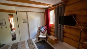 A cozy room with a bed, a chair, a small table, a TV, and a window with curtains. - Studio with terrace (7 minutes from Vercorin) (Chalais)