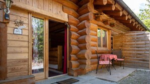 A log cabin with a wooden exterior, a door leading inside, and a small outdoor seating area with a table and chairs. - Studio with terrace (7 minutes from Vercorin) (Chalais)