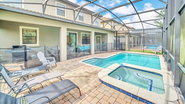 A covered outdoor swimming pool area with lounge chairs and a barbecue grill.
