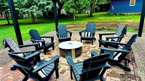 A patio with six Adirondack chairs and a round table, surrounded by a brick floor and a pergola structure. - Spacious 5-bedroom house in awesome Spirit Lake with WiFi, AC (Spirit Lake)