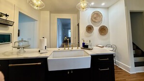 A modern kitchen with a large white sink, black cabinets, and a glass-top island. There are two pendant lights above the sink and a mirror above the countertop. - Spacious 5-bedroom house in awesome Spirit Lake with WiFi, AC (Spirit Lake)