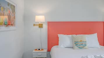 A hotel room with a bed, a nightstand, a lamp, and a painting on the wall.