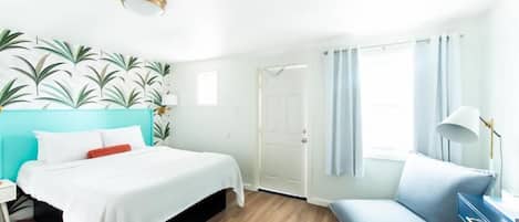 A modern hotel room with a bed, a desk, and a chair.