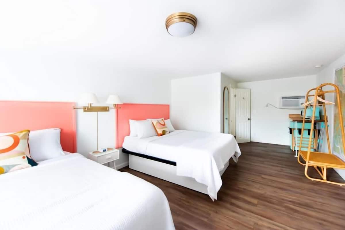 Ein Hotelzimmer mit zwei Betten, einem Schreibtisch, einem Stuhl, einer Karte an der Wand und einem Hängekorbsessel.
