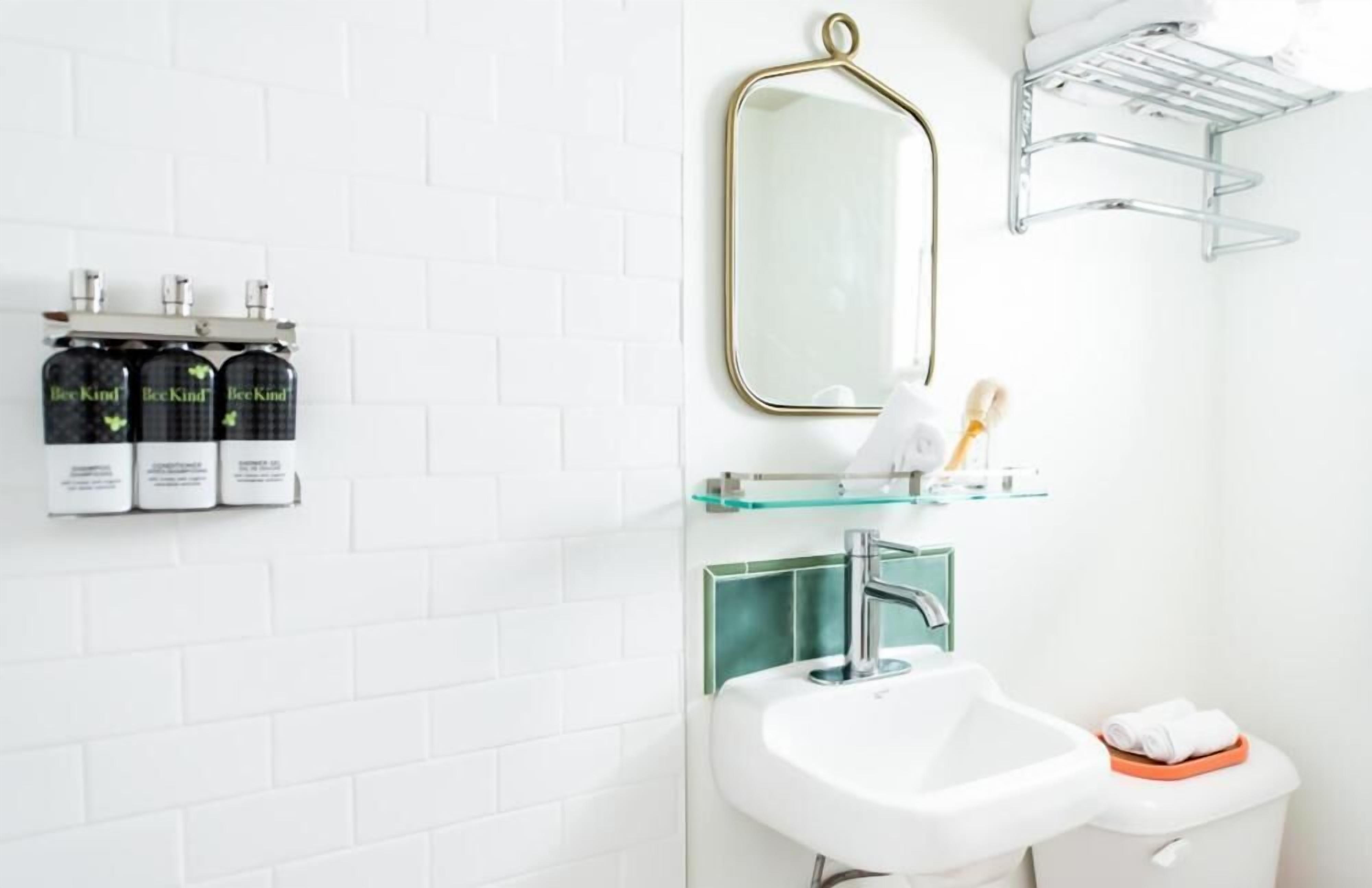 A bathroom with a white sink, a mirror, and a shelf with toiletries.