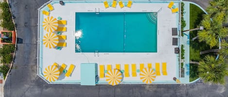An aerial view of a swimming pool area with multiple sun loungers and a pool.