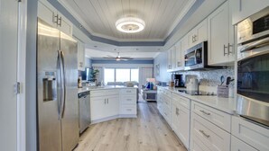 Une cuisine moderne avec des meubles blancs, des appareils en acier inoxydable et un plancher en bois.