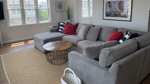 A modern living room with a grey sectional sofa, a round coffee table, and a ceiling fan.