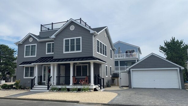 A two-story house with a front porch, a garage, and a covered patio.