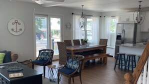 A spacious living area with a dining table, chairs, and a kitchen area with a refrigerator.
