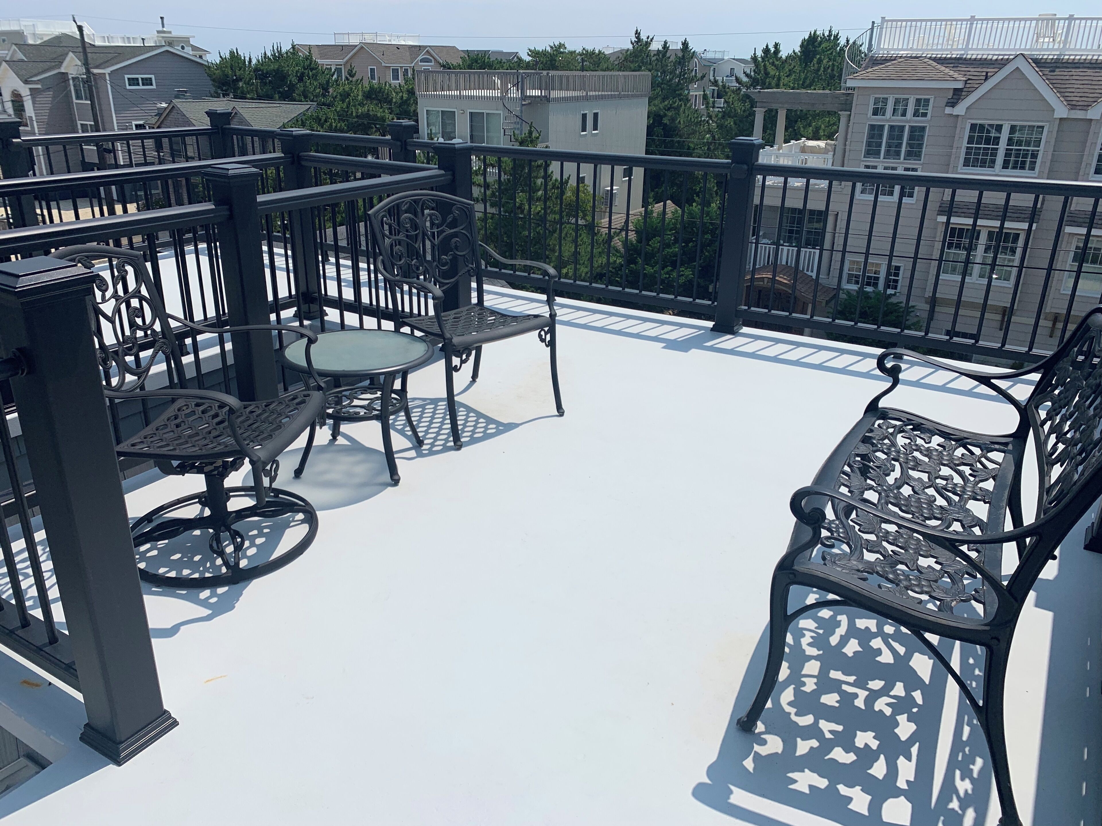 A rooftop patio with outdoor furniture, including a table and chairs, and a railing.