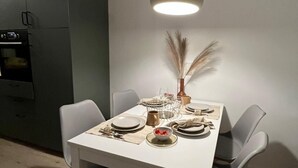 A dining area with a white table set for four, surrounded by grey chairs. A modern pendant light hangs above the table. - Fisherman's chic "Die Bude" at the port of Maasholm (Maasholm)