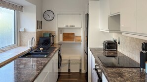 Una cucina moderna con piani in granito, lavastoviglie integrata, frigorifero e un orologio a parete.