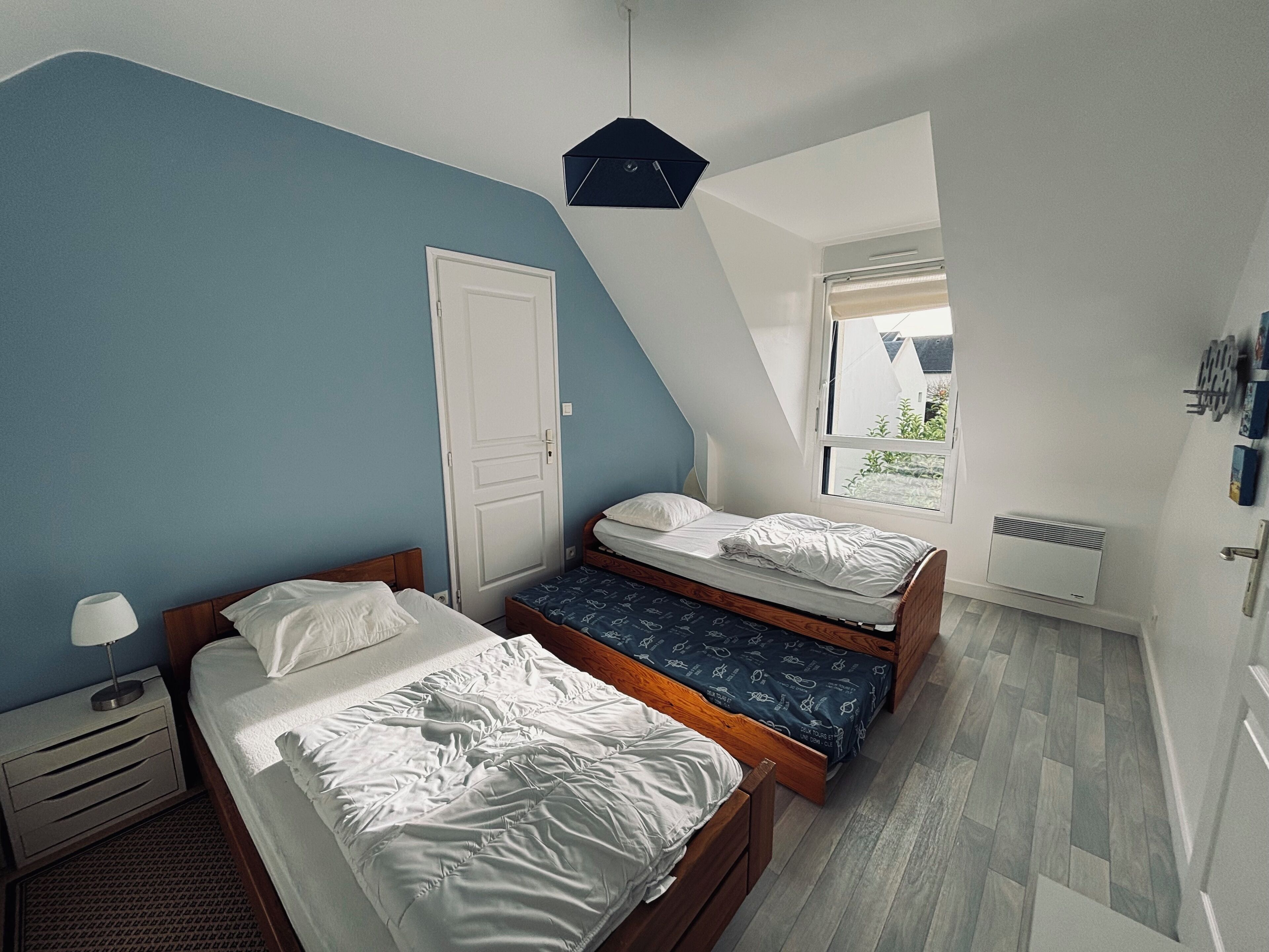 Una camera da letto con due letti, una porta bianca, una finestra e una lampada a soffitto.
