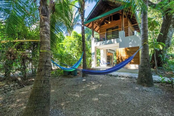 Une maison en bois avec un hamac, située dans un cadre tropical.
