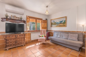 Una sala de estar con televisor, sofá y un cuadro en la pared.