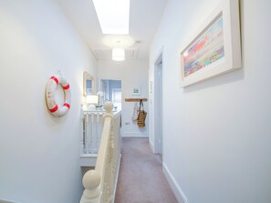 A hallway with a white railing, a life preserver decoration, a mirror, and a framed picture on the wall. - 3 bedroom accommodation in Llanbedr Nr Harlech (Llanbedr Nr Harlech)
