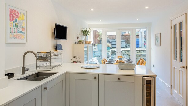 Een moderne keuken met een inbouwoven, een spoelbak en een eethoek met een tafel gedekt voor twee personen.