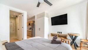 Een moderne hotelkamer met een groot bed, een bureau, een stoel, een televisie en een douche.