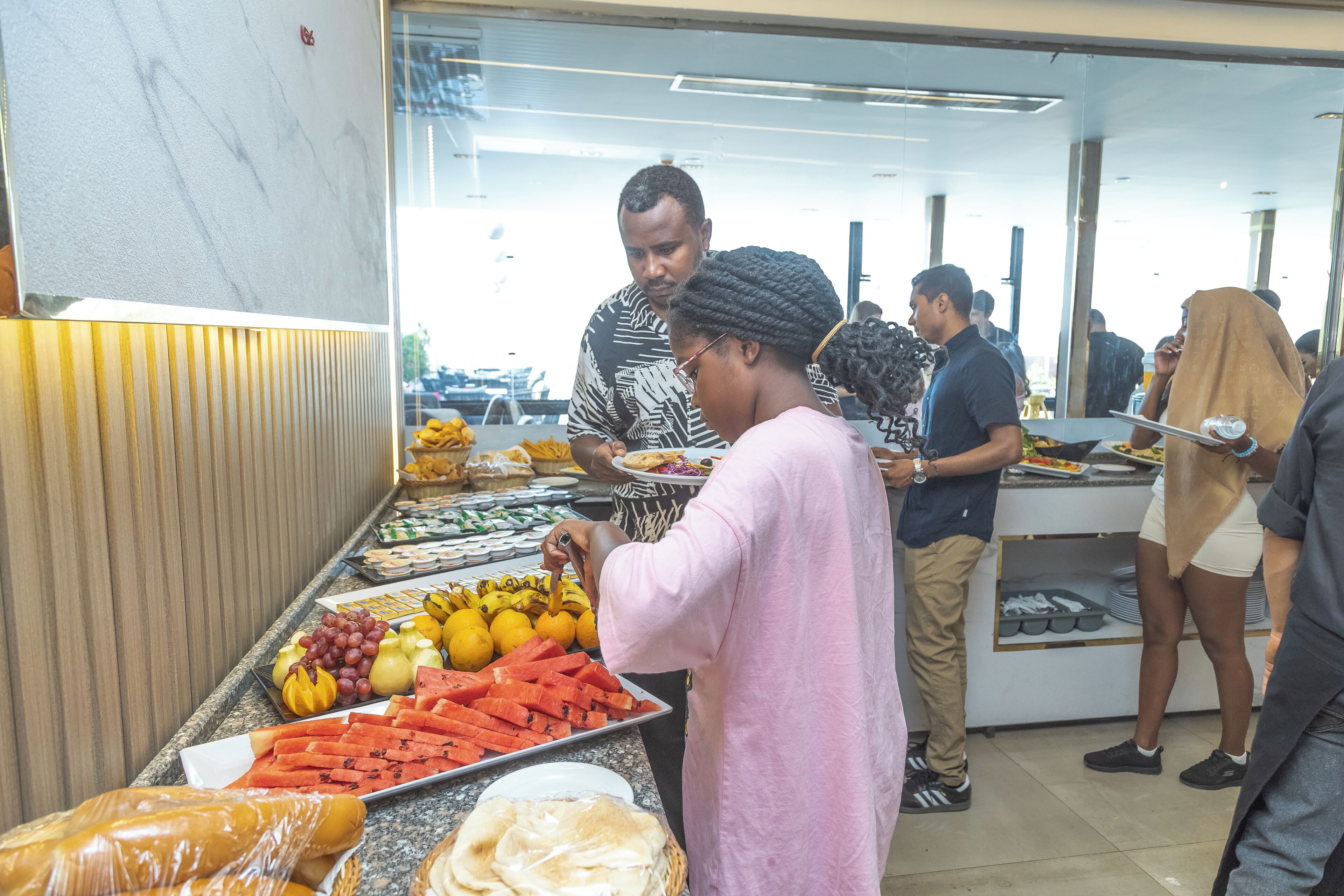 A buffet with various food items including fruits, vegetables, and bread.