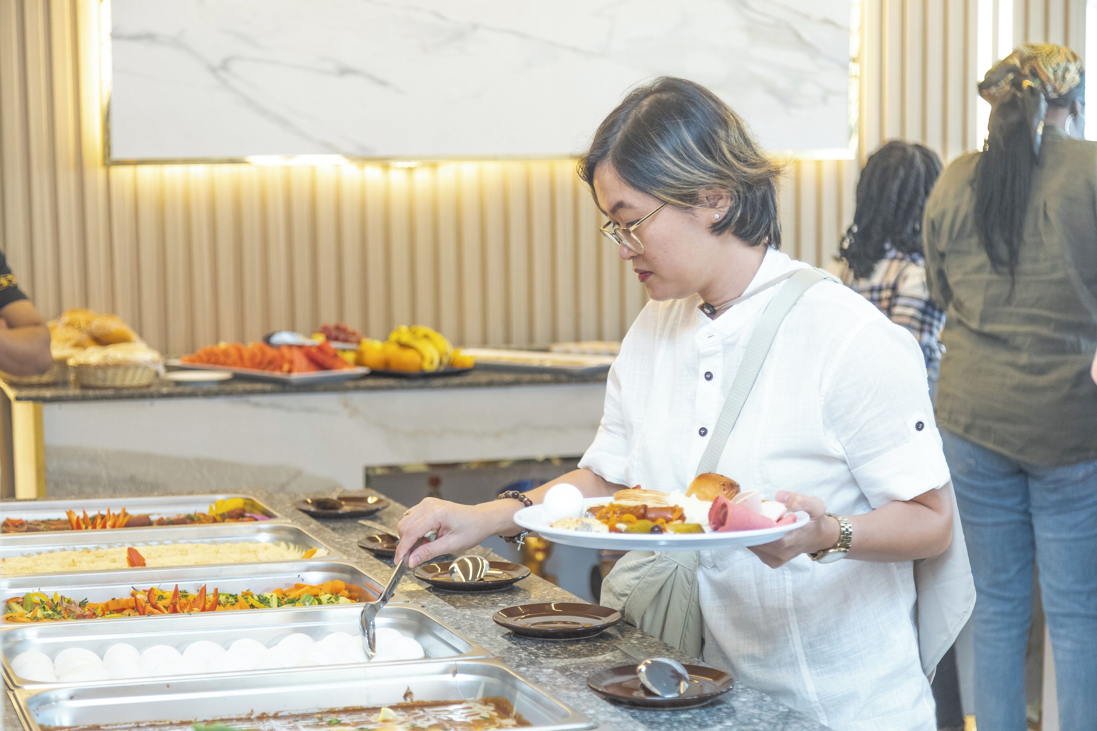 A buffet setup with various food items and a person serving food.