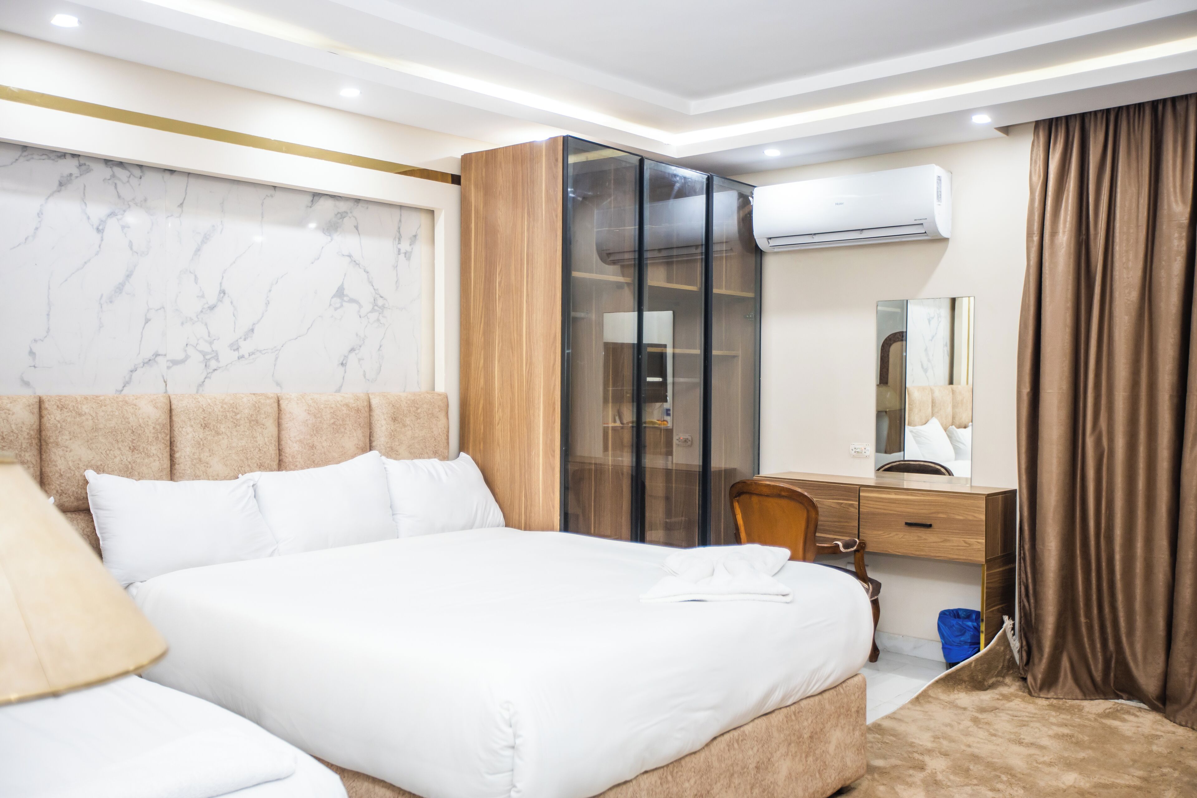 Une chambre d’hôtel avec un grand lit, un bureau avec une chaise, une armoire et un appareil de climatisation.