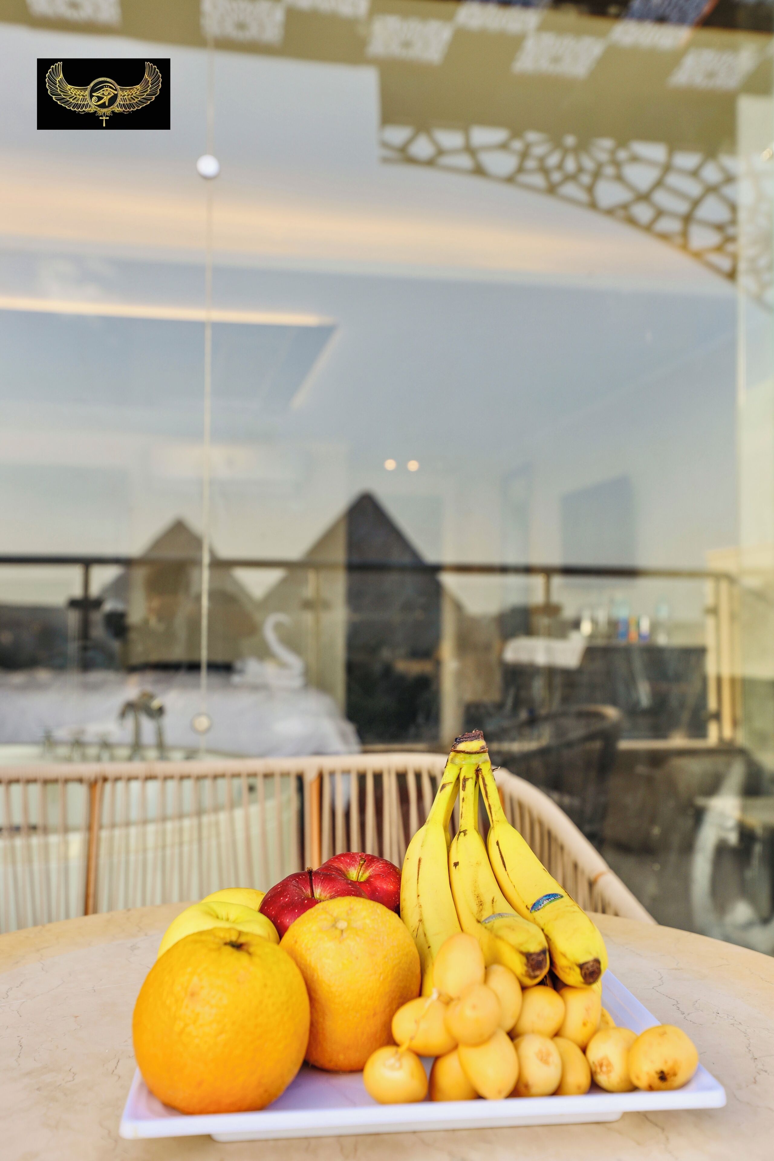 A fruit platter on a table with a view of a building and a balcony in the background.