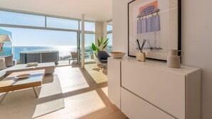 A modern living room with a large window, a sofa, a coffee table, and a minimalist decor style.