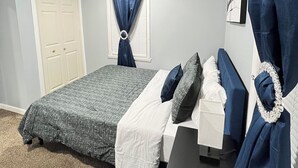 A bedroom with a bed, a desk, a chair, a window with curtains, and a door. - Cozy 2-bedroom apartment in charming New Britain with WiFi (New Britain)