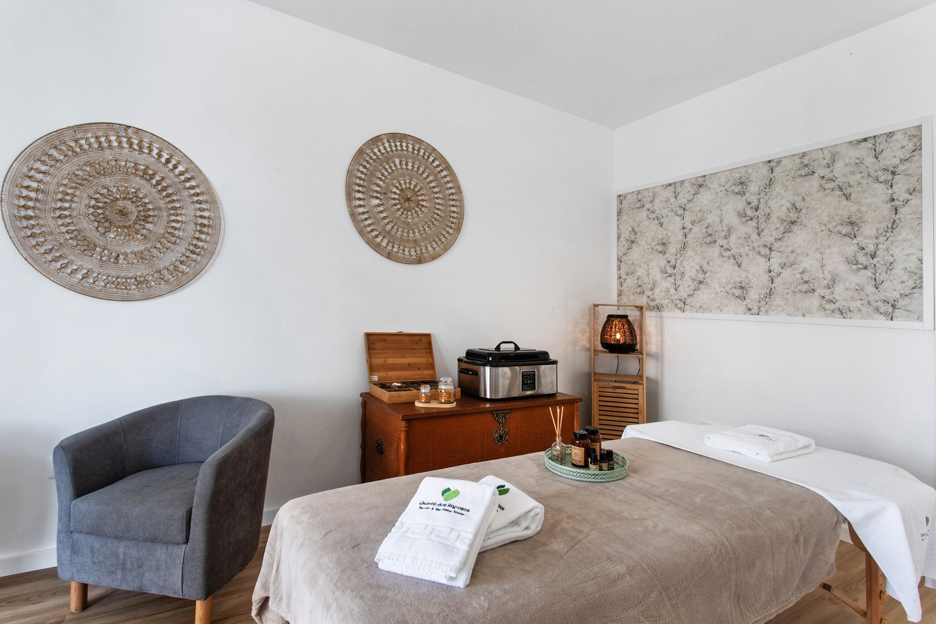 A room with a bed, a chair, a wooden chest, and wall decor.