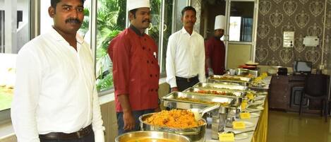 A buffet setup with multiple food stations, including a rice dish and a curry.