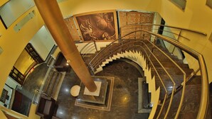 A spiral staircase with a marble floor and a large column in the center. - Hotel Priso (Puducherry)
