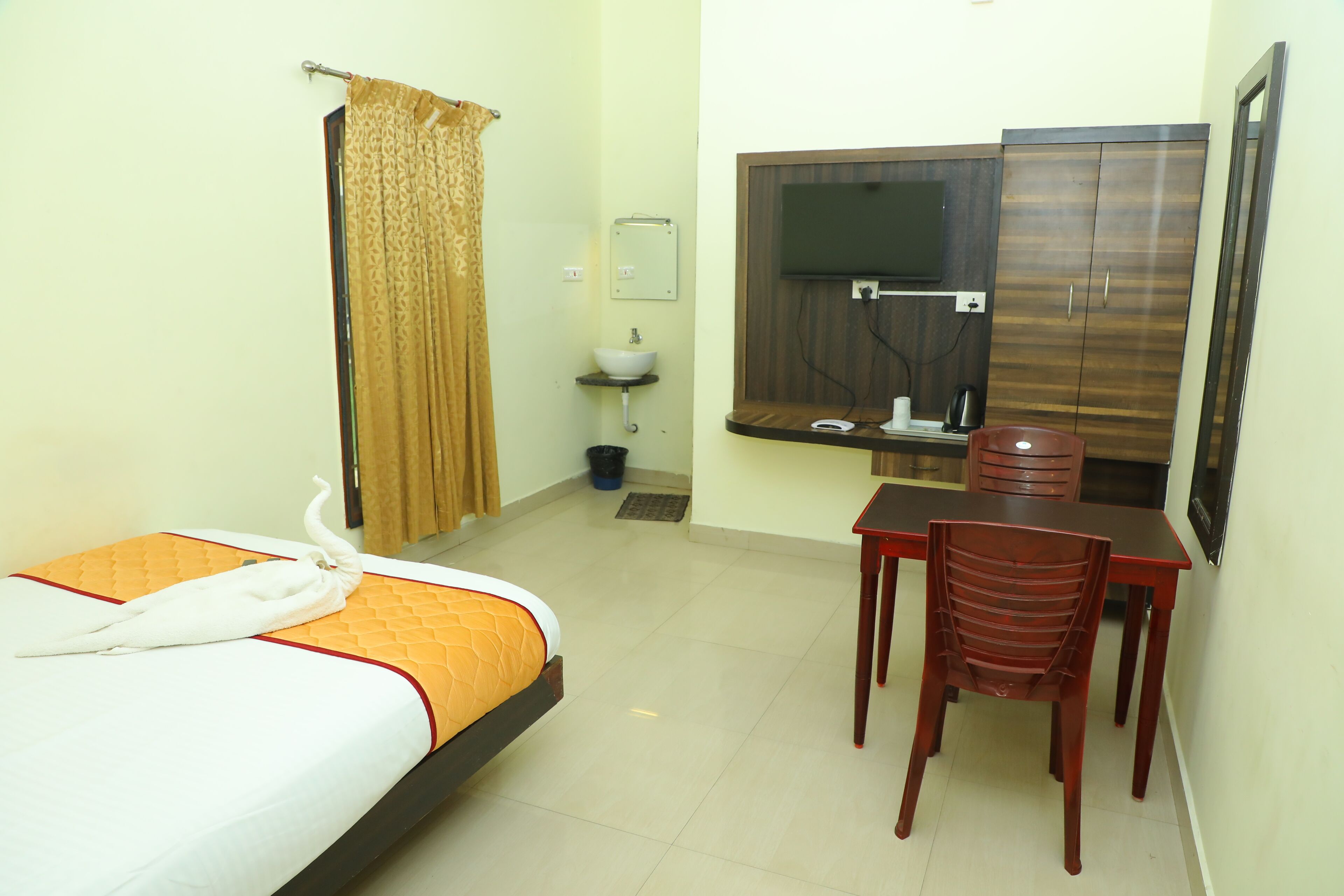 A hotel room with a bed, a desk, a chair, a television, and a wardrobe.