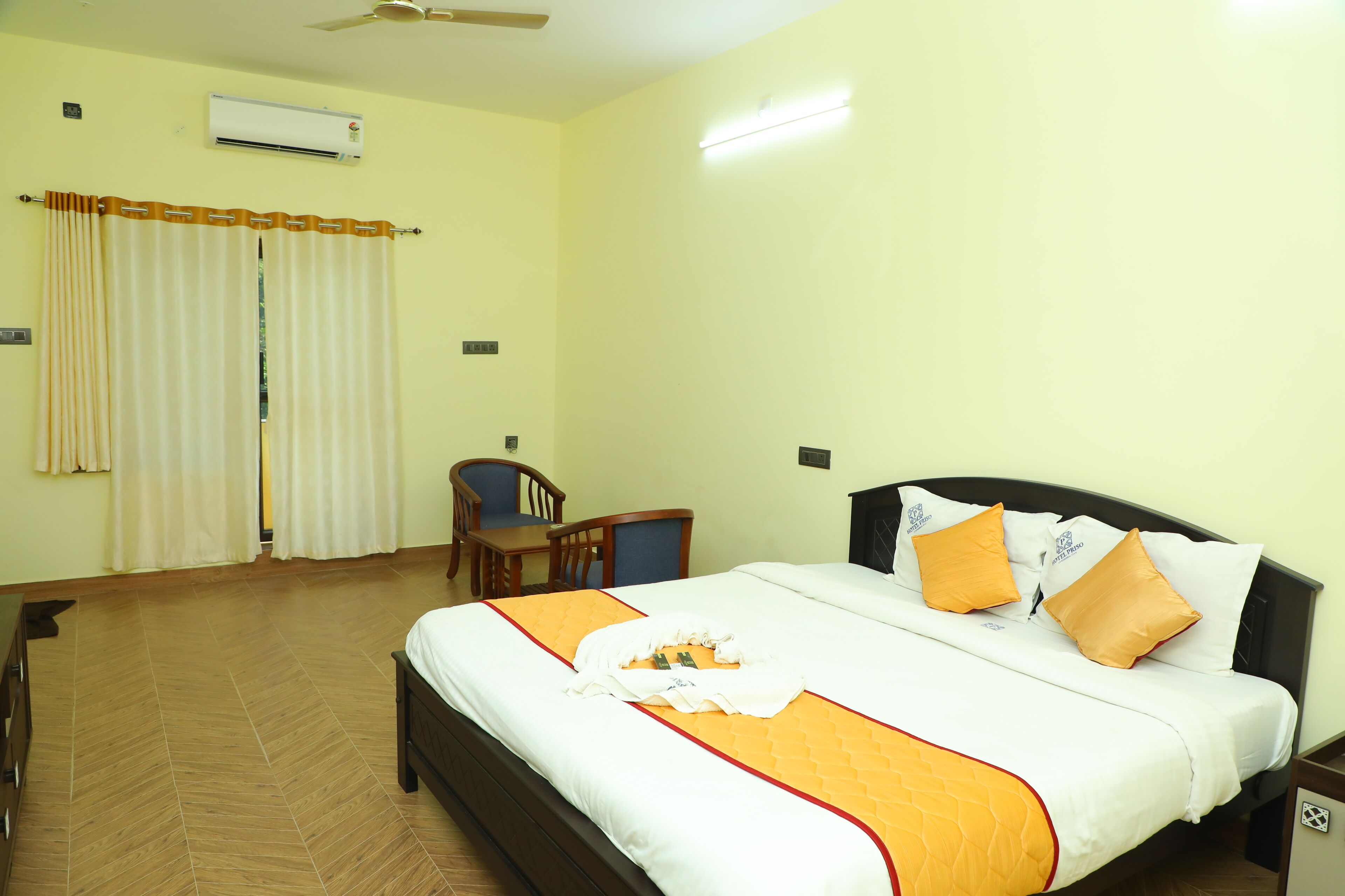 Habitación de hotel con cama, escritorio, silla y ventilador de techo.