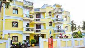 A multi-story hotel with balconies and a signboard indicating a restaurant. - Hotel Priso (Puducherry)