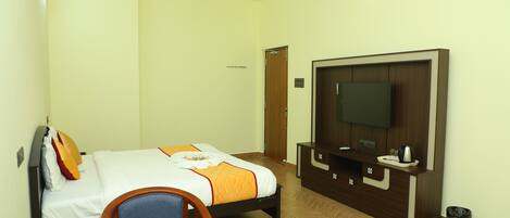 Una habitación de hotel con una cama, televisión, escritorio y una silla.