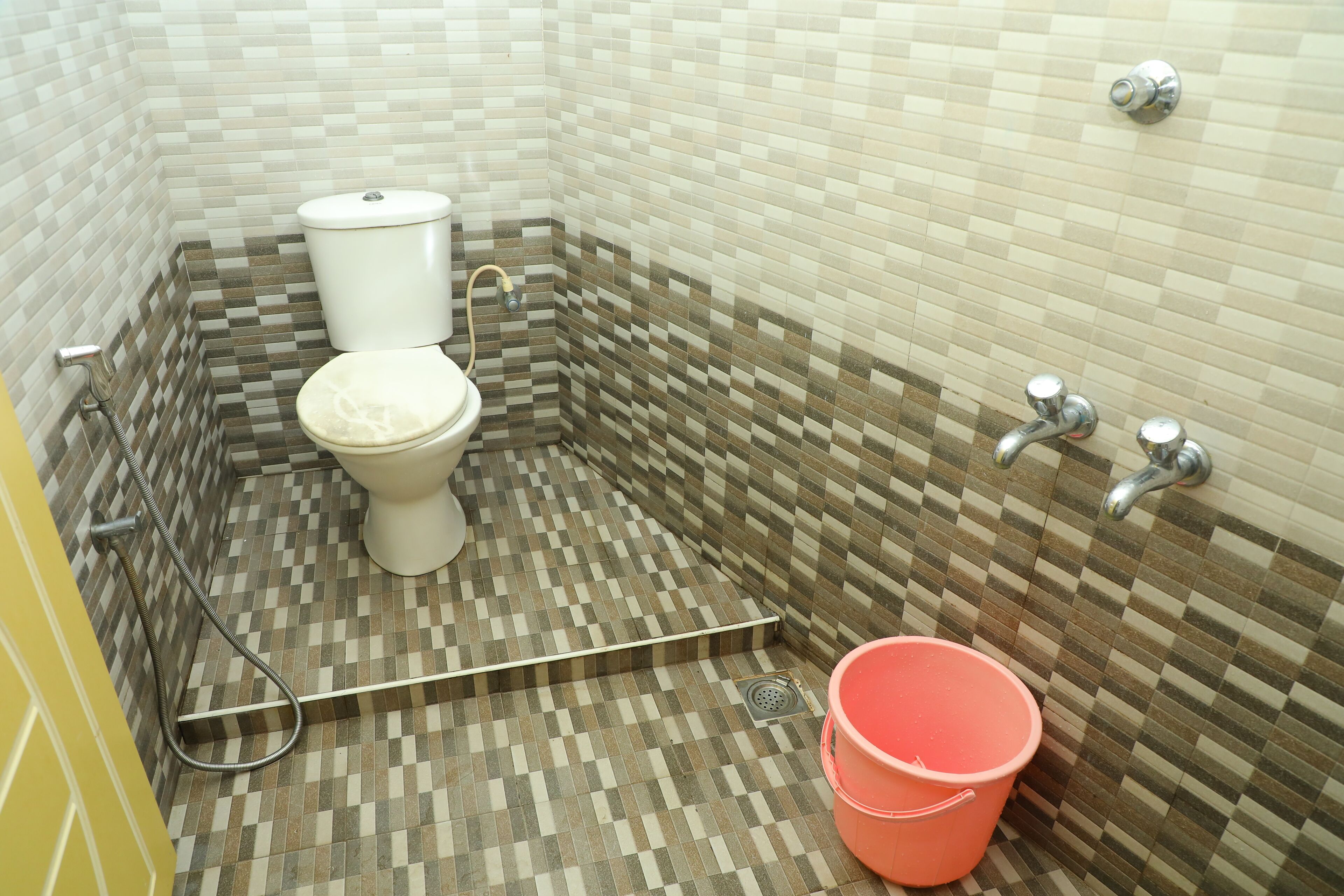 Ein Badezimmer mit Toilette, Dusche und Eimer.