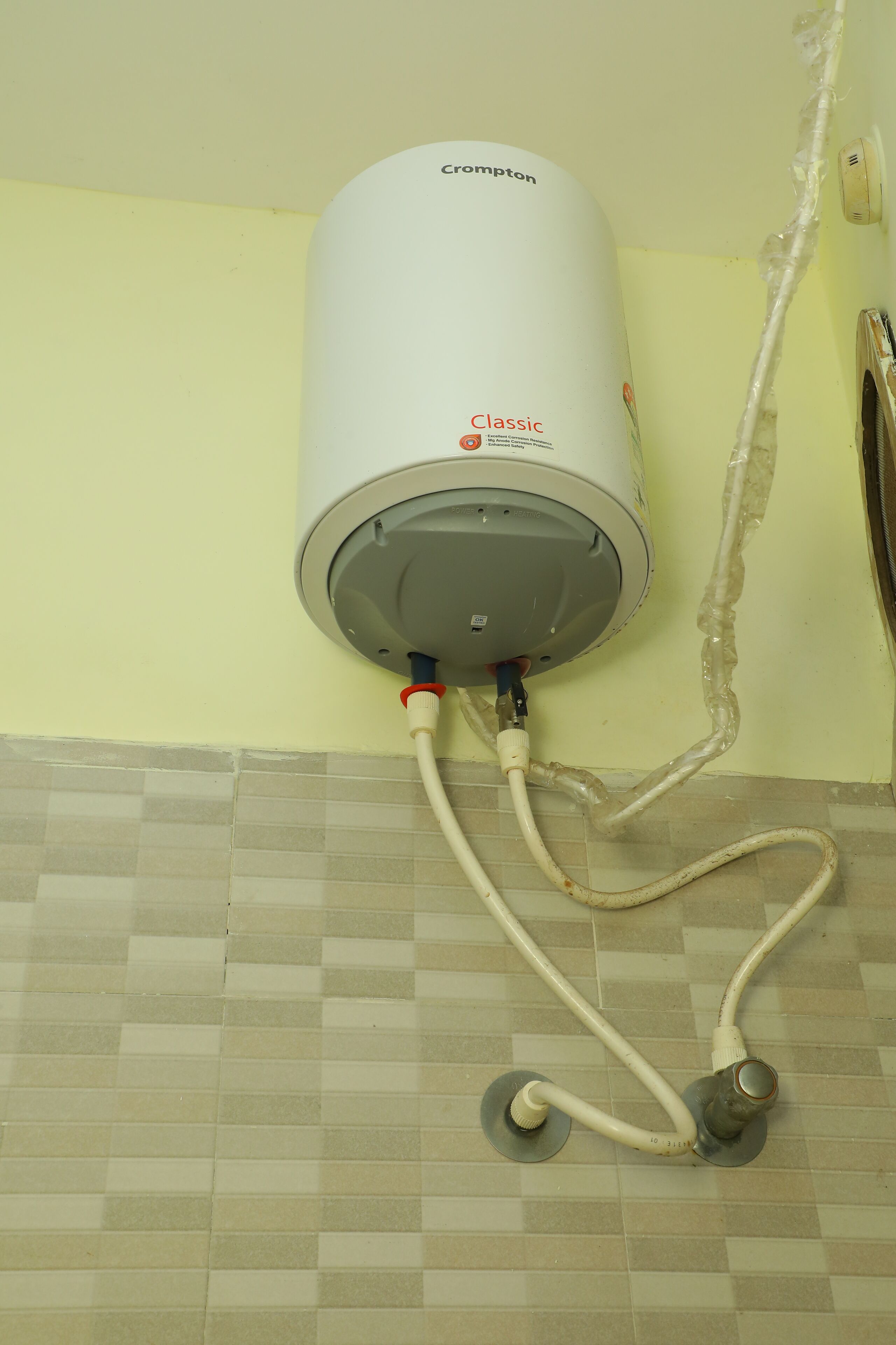 Scaldacqua montato su una parete con pavimento piastrellato.