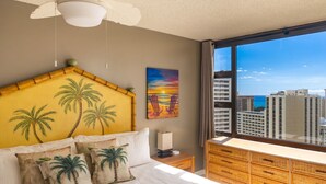 Une chambre d’hôtel avec un lit, une table de chevet, une commode, un tableau et une vue sur des immeubles de grande hauteur.