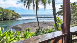 Una playa con una terraza de madera y vegetación tropical.