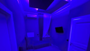 Una habitación con una cama, un televisor de pantalla plana en la pared y una puerta.