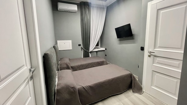 Un dormitorio con cama, aire acondicionado, televisión y una puerta.