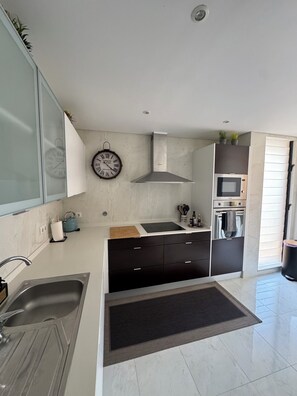 A modern kitchen with a built-in oven, microwave, and stainless steel sink.