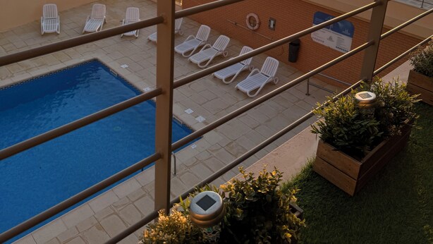 A rooftop pool area with lounge chairs and a view of the sunset over the ocean. - 1 Bedroom Areia Branca Beach (Lourinhã)