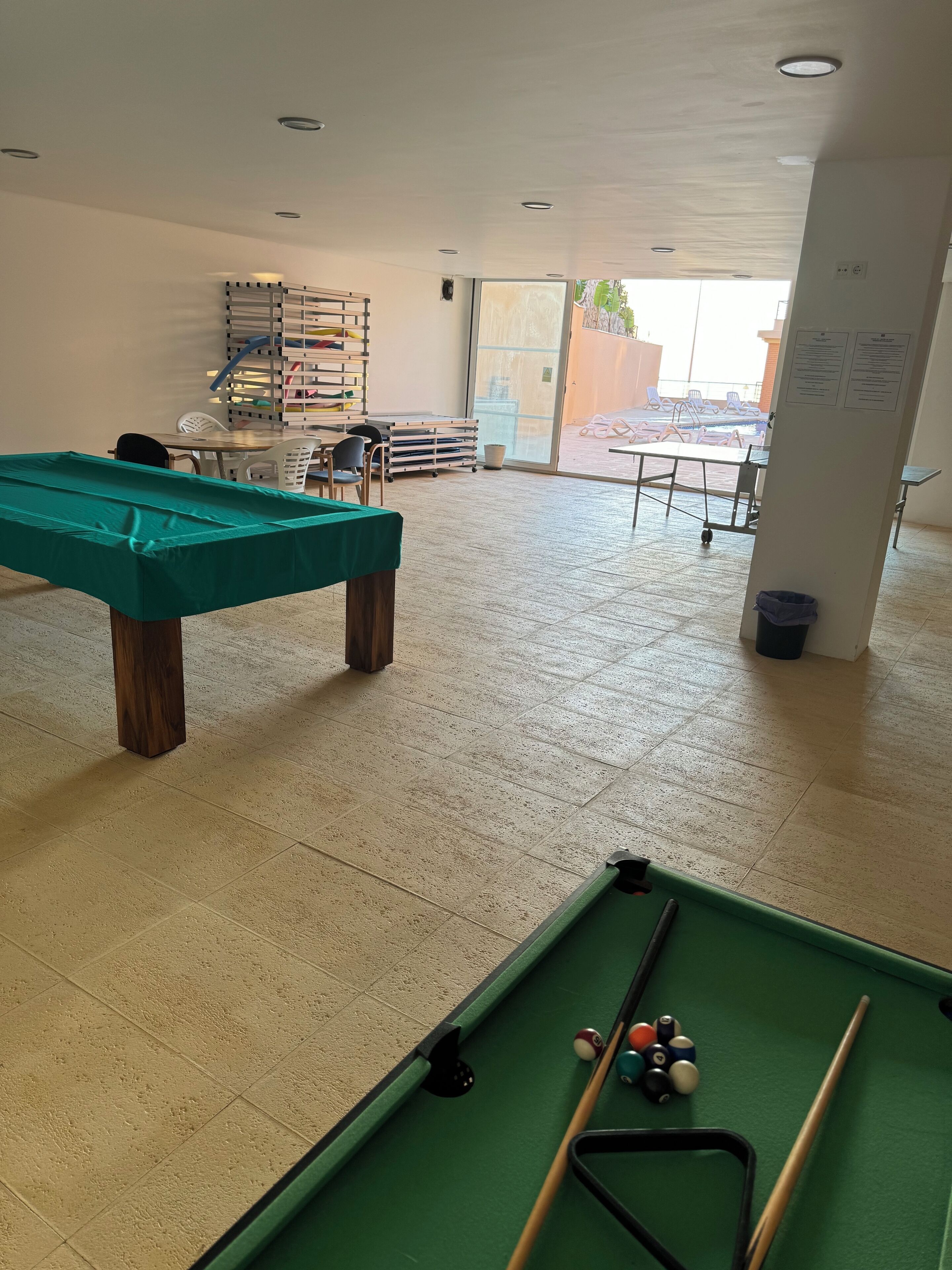 Een pooltafel met ballen, een groene pooltafel en een standaard met poolkeus.