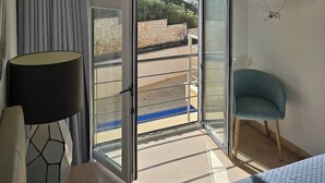 A hotel room with a balcony, a TV mounted on the wall, and a view of the sea. - 1 Bedroom Areia Branca Beach (Lourinhã)