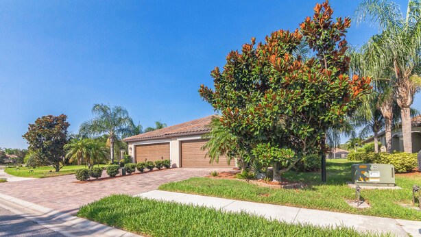 A residential driveway with a garage, a well-maintained lawn, and mature trees.