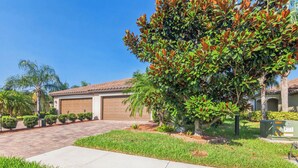 A residential property with a garage, a driveway, and well-maintained landscaping including grass and trees.
