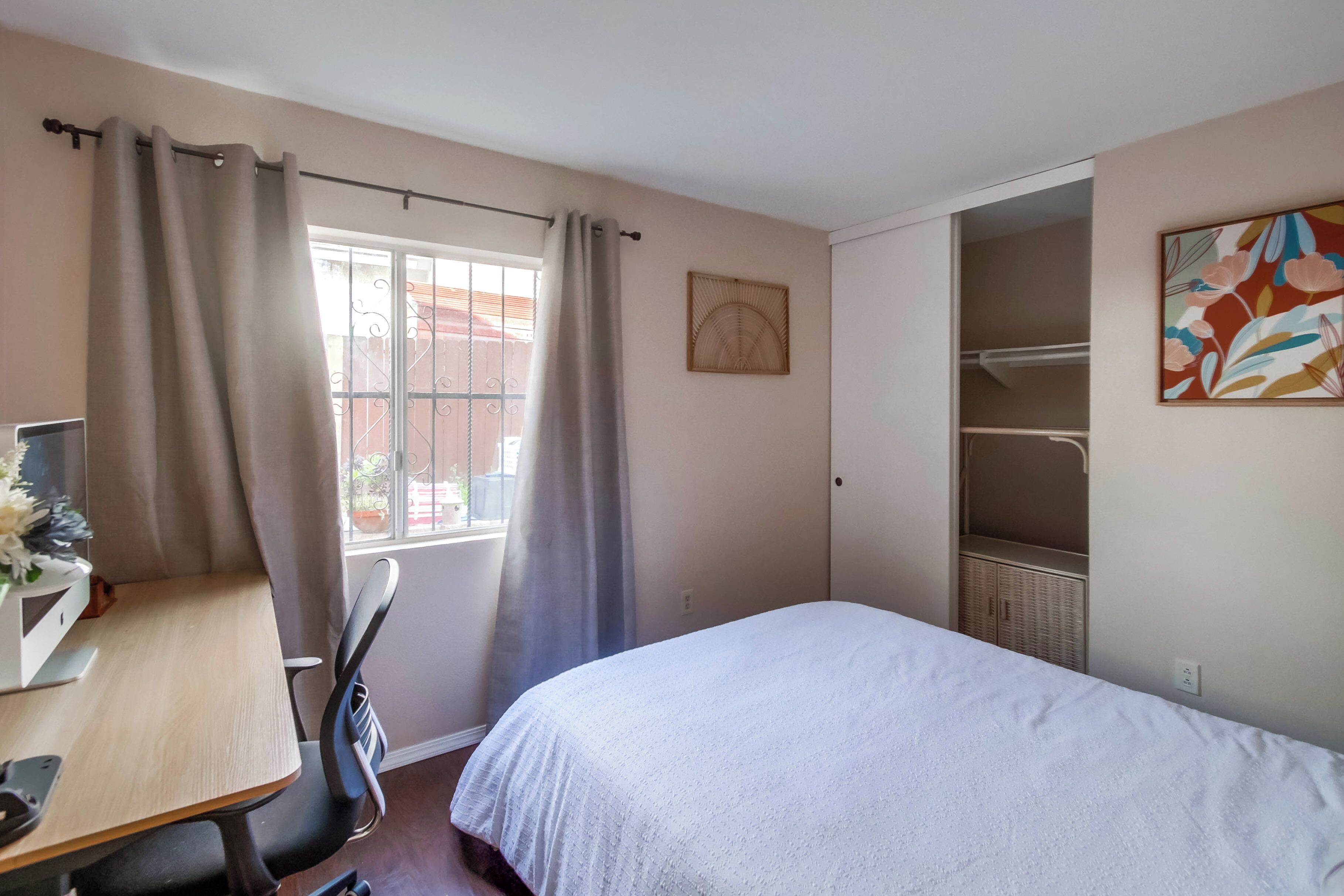 A bedroom with a bed, a desk, and a wardrobe.