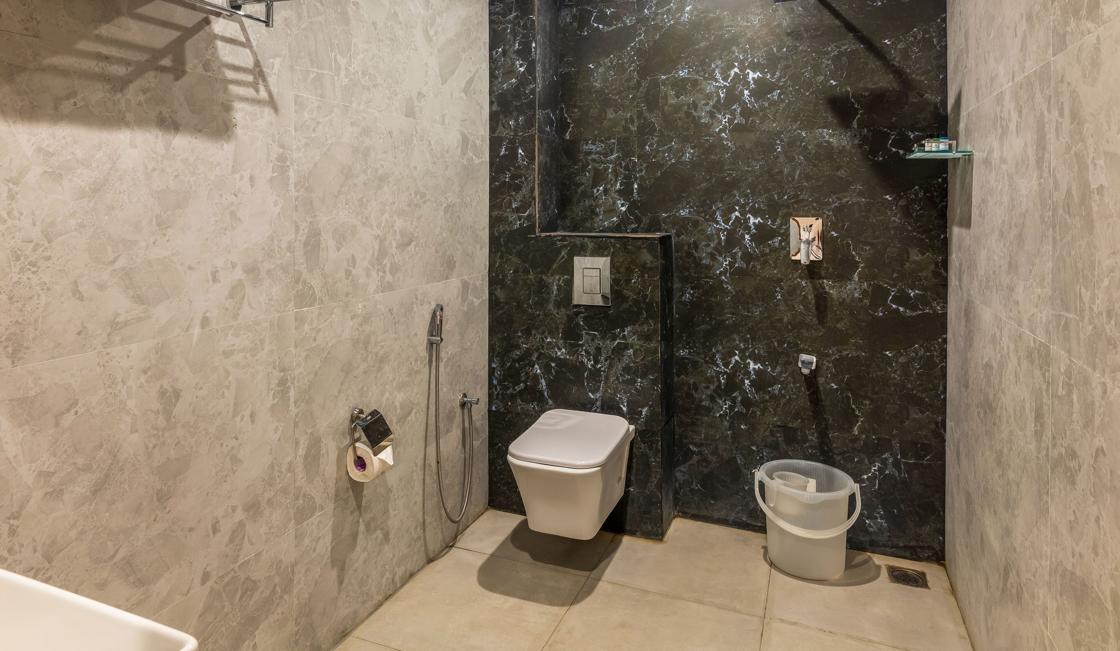 A modern bathroom with a toilet, shower, and a small trash bin.
